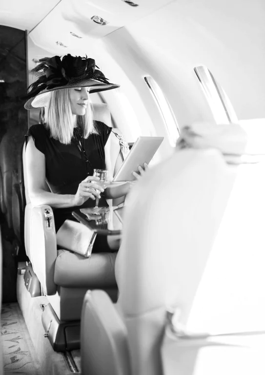 Woman With Drink Using Digital Tablet In Private Jet