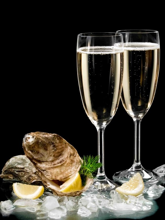 Two champagne glasses and oysters shells on black background