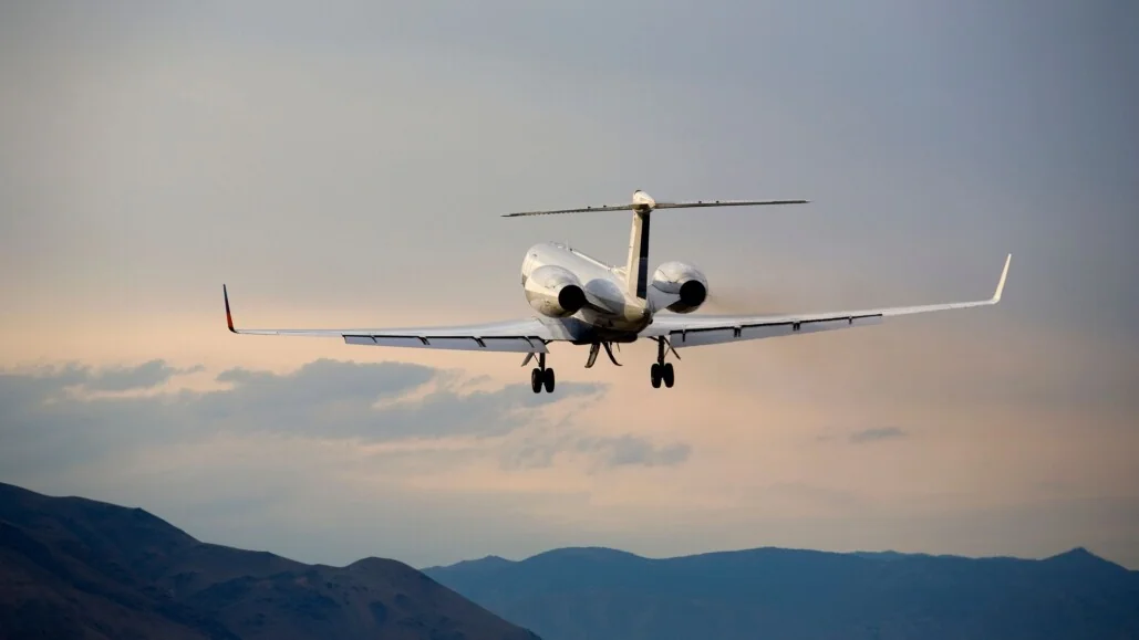 White private jet flying over the mountains