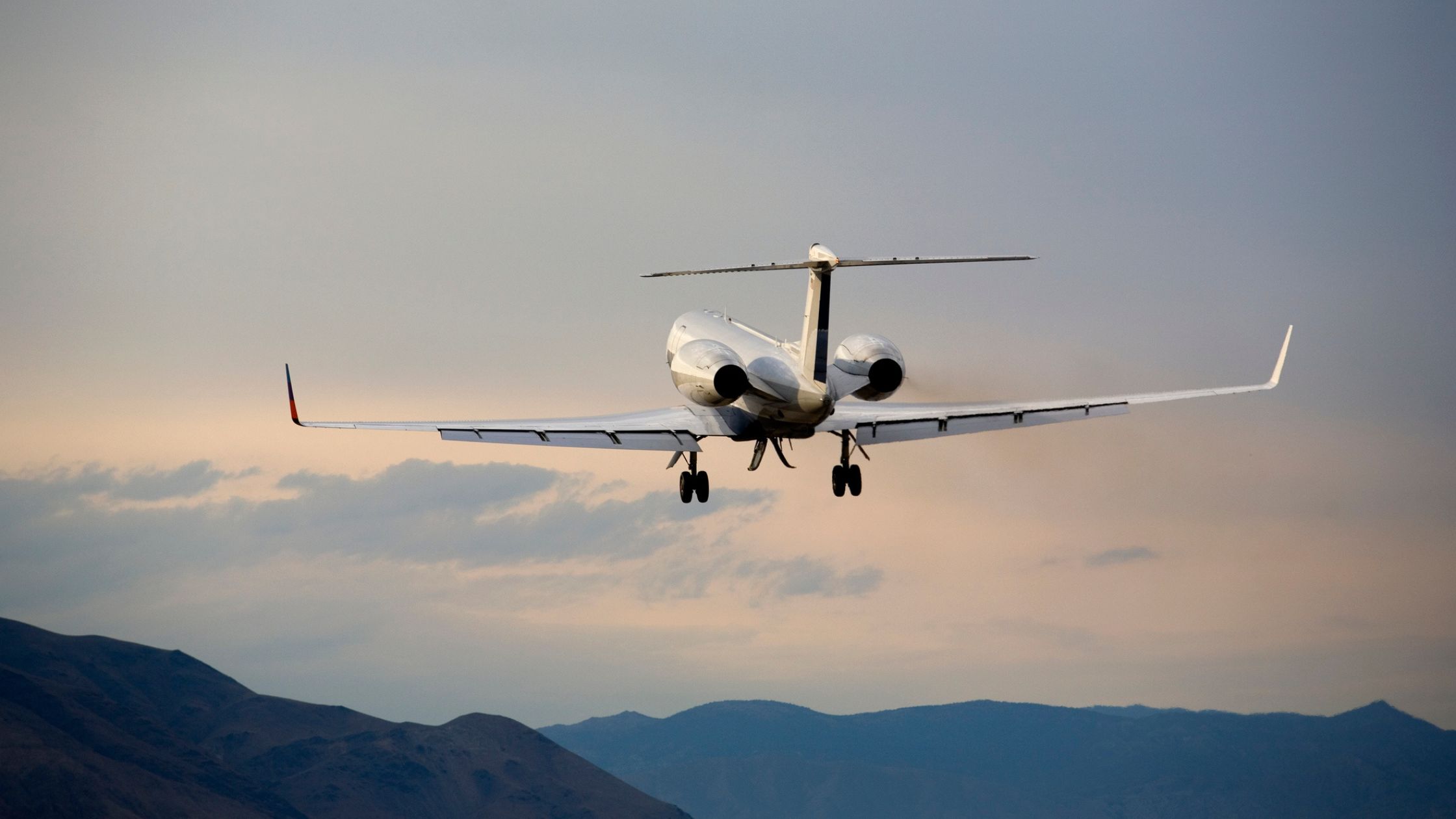White private jet flying over the mountains