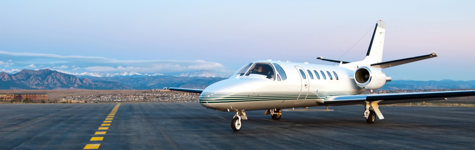 Private jet on an airport taxiway with mountains in the background